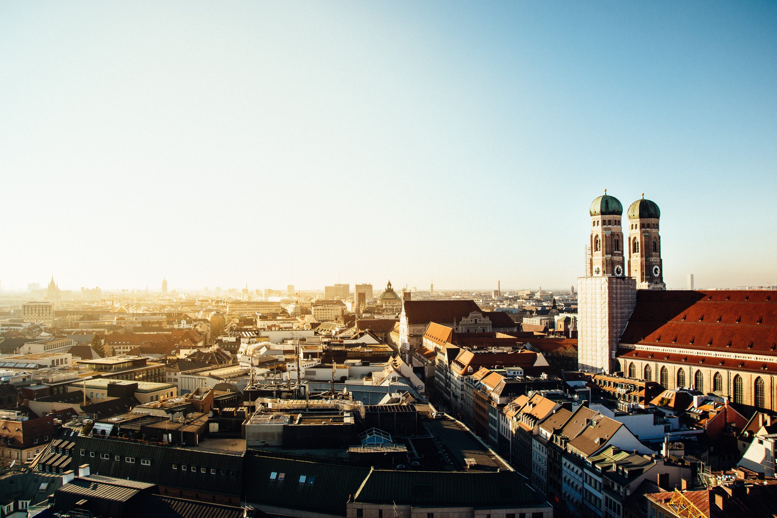 Blick von oben auf München mit Frauenkirche und Sonnenaufgang.